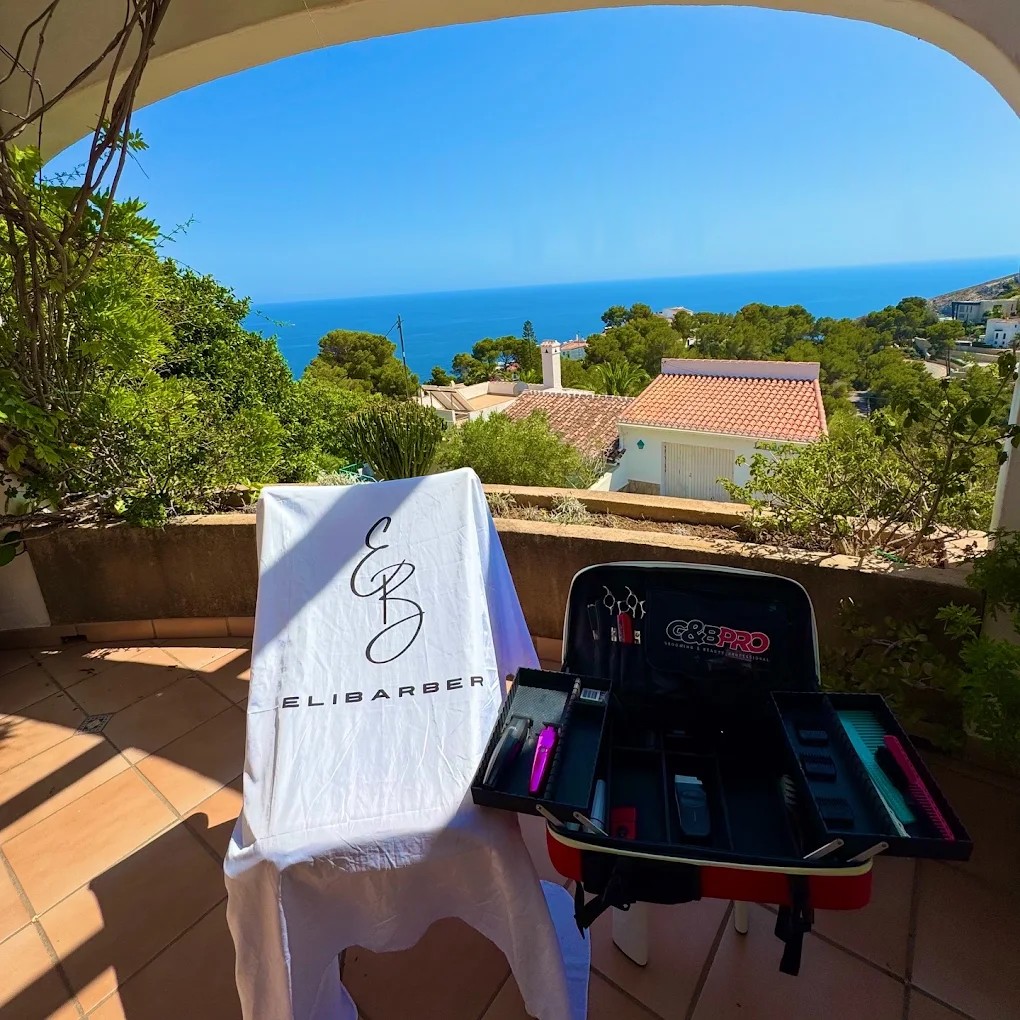 Silla con la capa de Ali Barber y maletín profesional en una terraza con vistas al mar